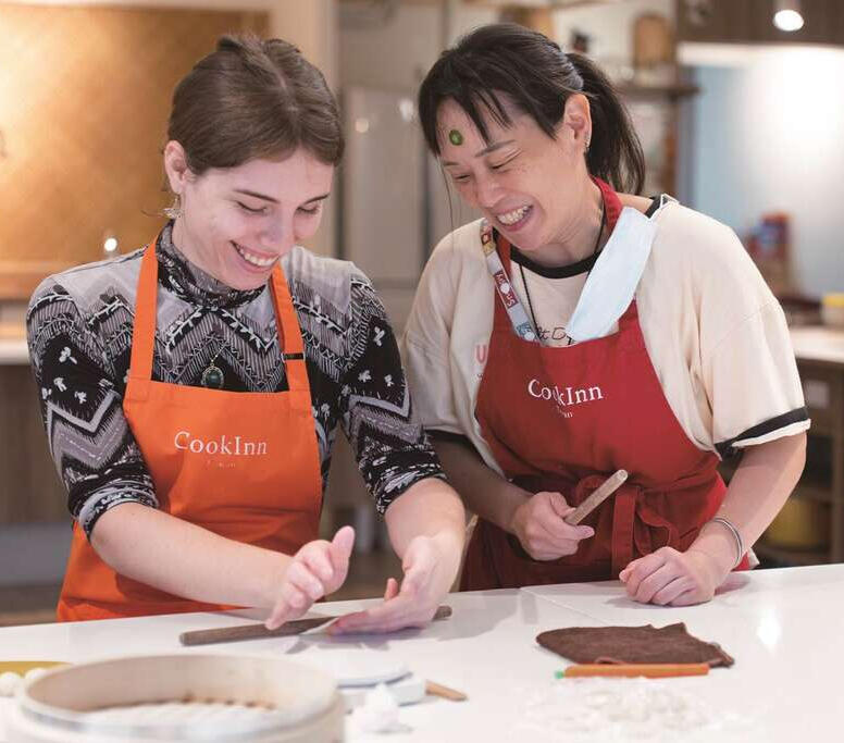 Teacher Angela and I rolling out dumpling dough sharing a laugh